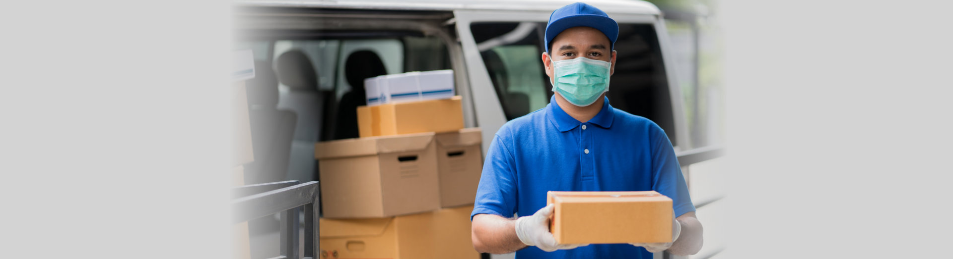 man holding parcel cardboard box wearing protection mask and medical rubber gloves standing in front of the van